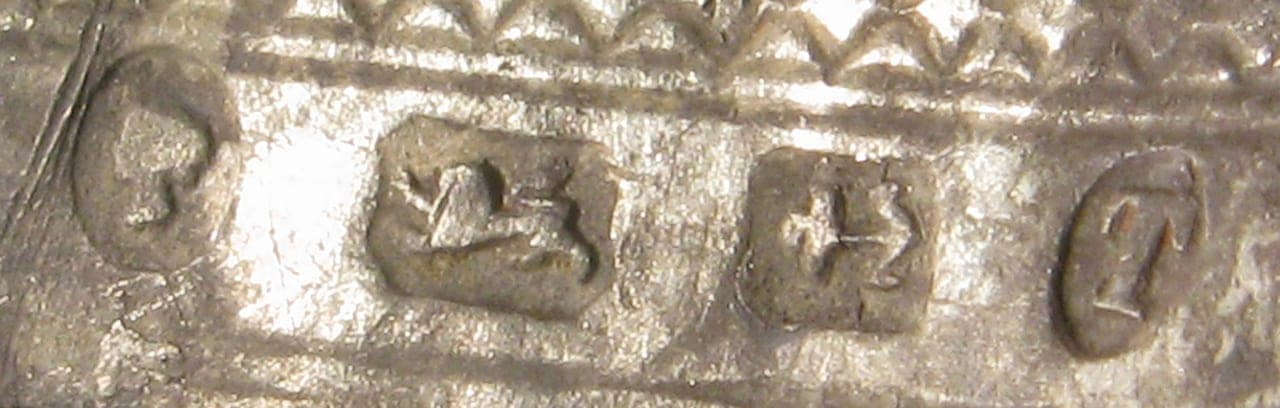 Close-up of a row of British silver hallmarks struck on a piece (lion passant visible) — illustrating the hallmarking/assay trade