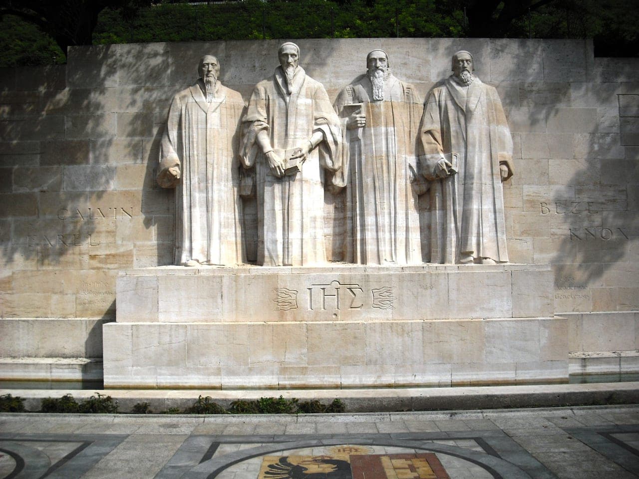 The Reformation Wall / statue of John Calvin in Geneva — the figure behind the 1541 ban that turned goldsmiths to watchmaking