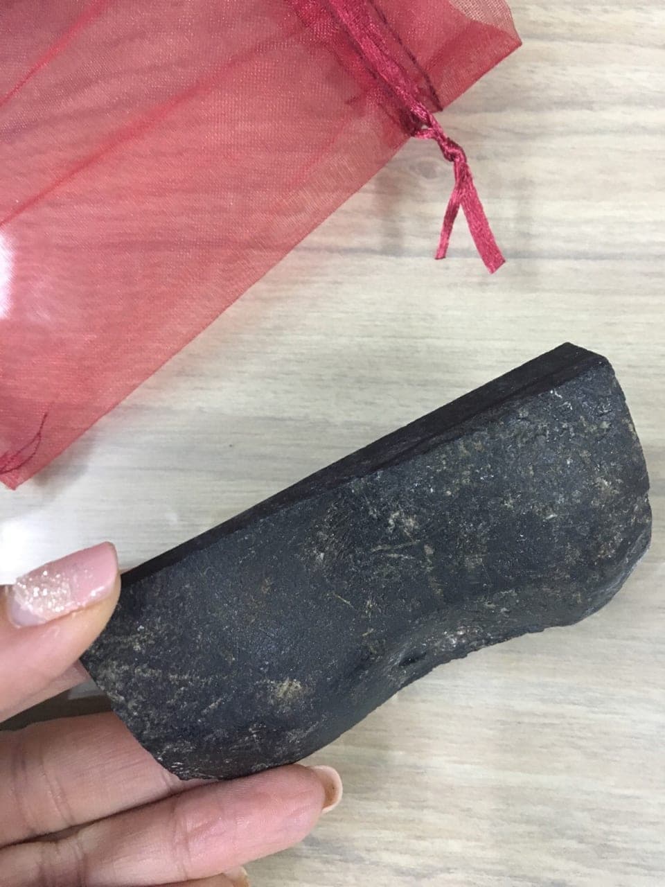 Rough jadeite boulder with its natural outer skin held in hand — raw jade as assessed before carving