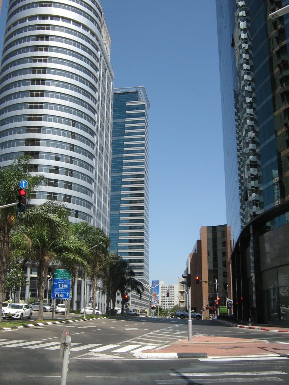 Street-level / pedestrian view of the Diamond Exchange District in Ramat Gan — the secured corporate streetscape at the base of the towers