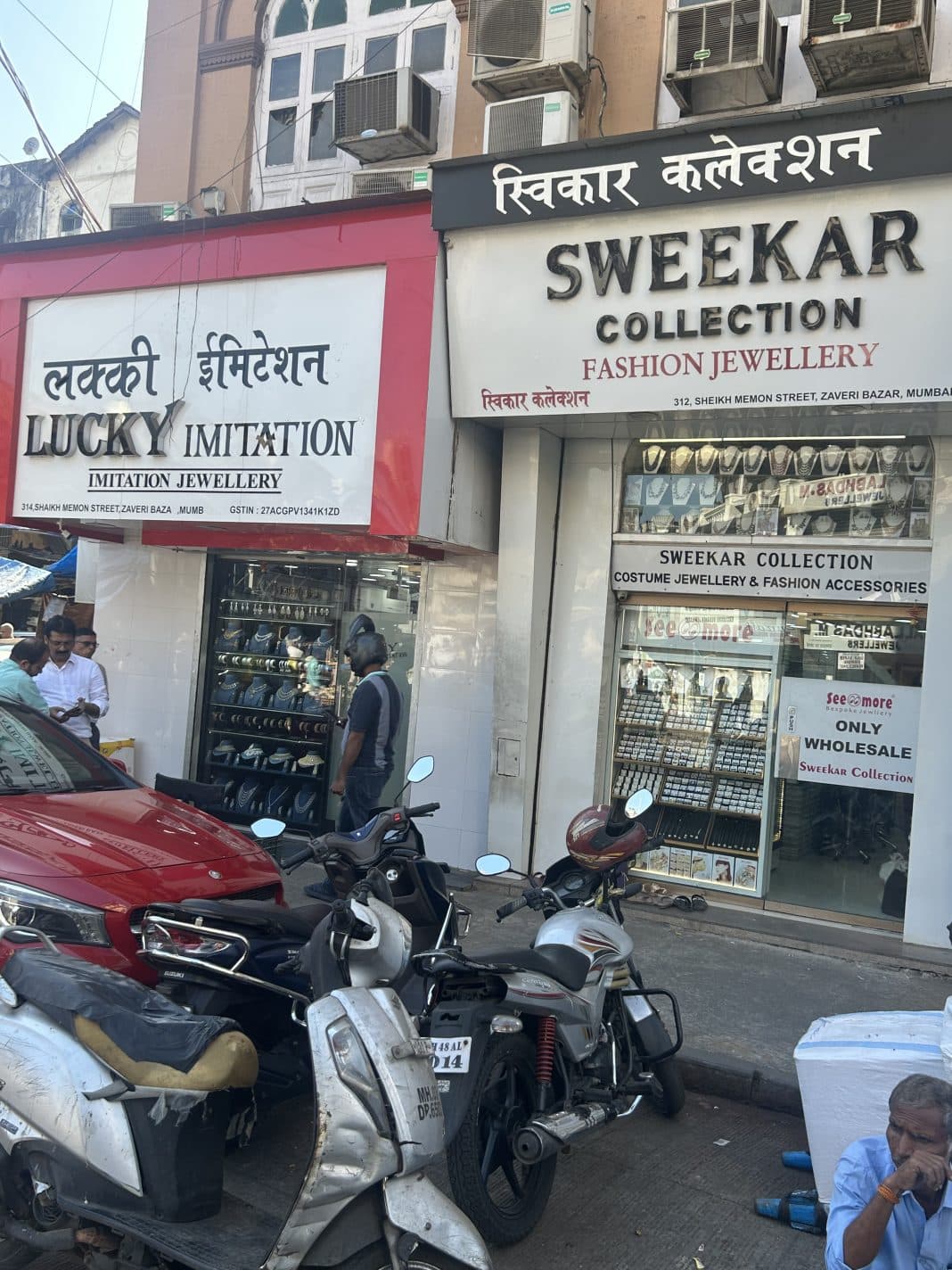 Street scene in Zaveri Bazaar showing Lucky Imitation and Sweekar Collection jewellery shops with motorcycles parked in front