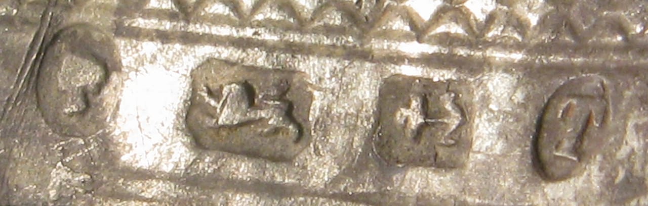 Close-up of a row of British silver hallmarks struck on a piece (lion passant visible) — illustrating the hallmarking/assay trade