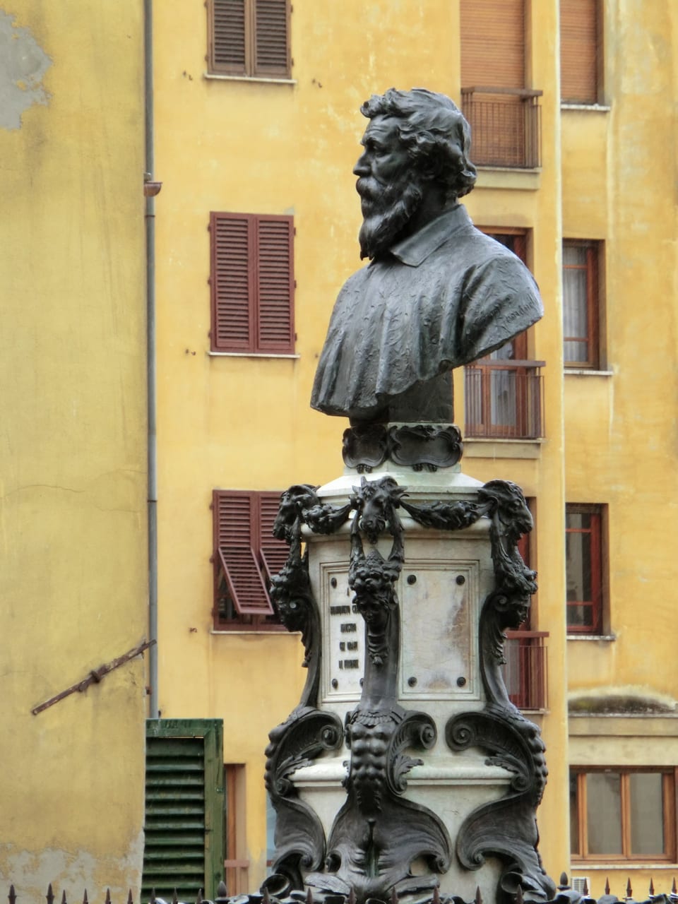 The bronze bust monument of Benvenuto Cellini at the centre of the Ponte Vecchio, on its pedestal by the open-air arches
